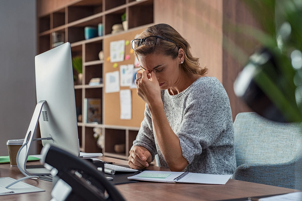 A woman at a desk resting her head on her hand while reading a legal question on her computer